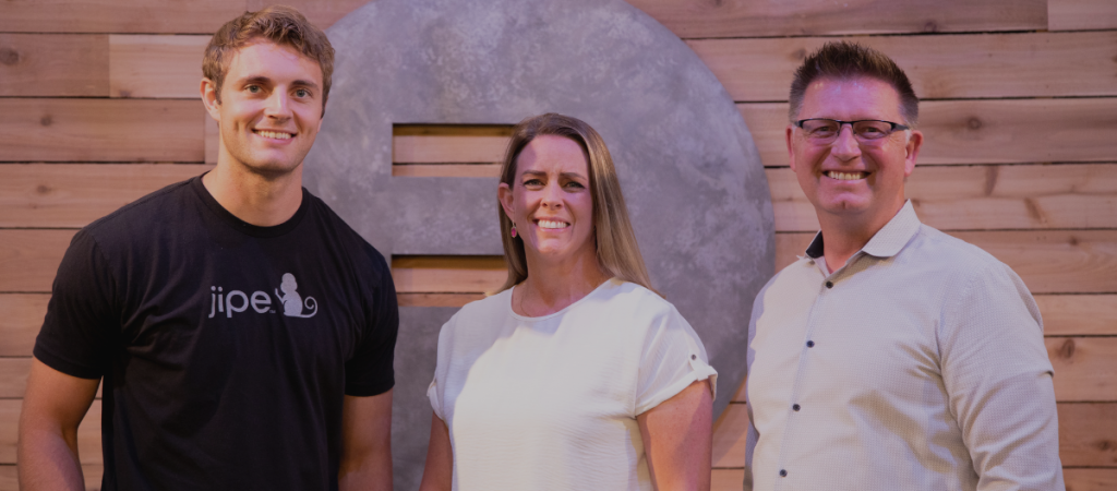 RevRoad's CEO Derrin Hill smiles alongside founder of Jipe Brenda Anderson and sales rep Jonathan Christensen as Jipe becomes the newest RevRoad portfolio company.
